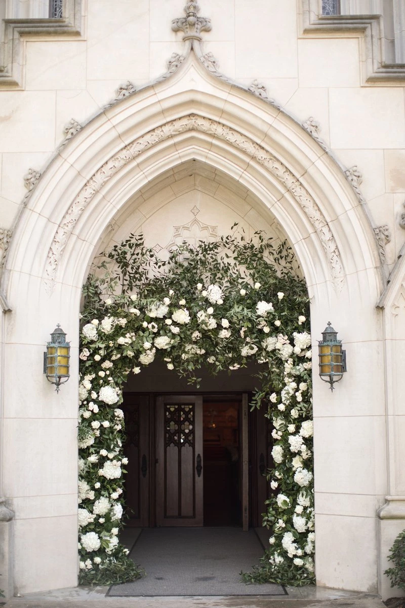 A church entrance framed with white flowers for a wedding ceremony.
