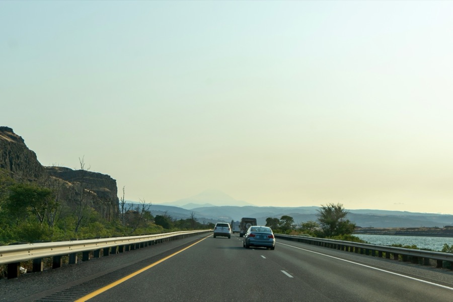 A highway runs between rocky cliffs and a stretch of water.