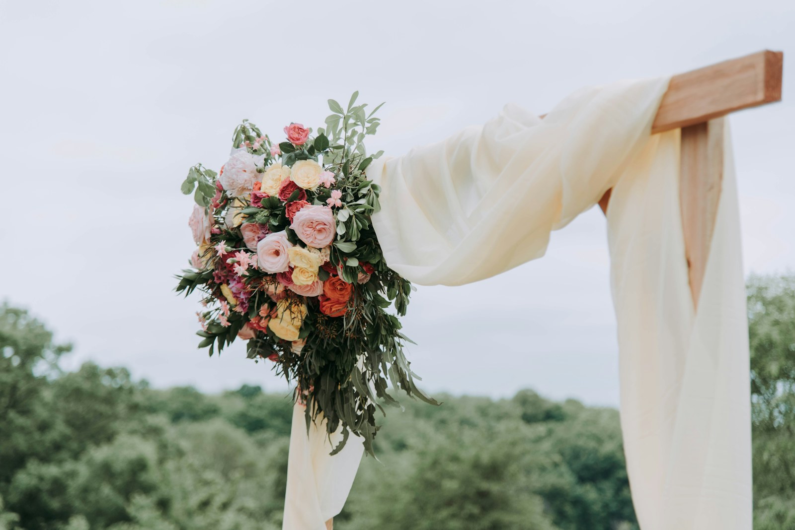 A flower arrangement on a simple outdoor ceremony arch.